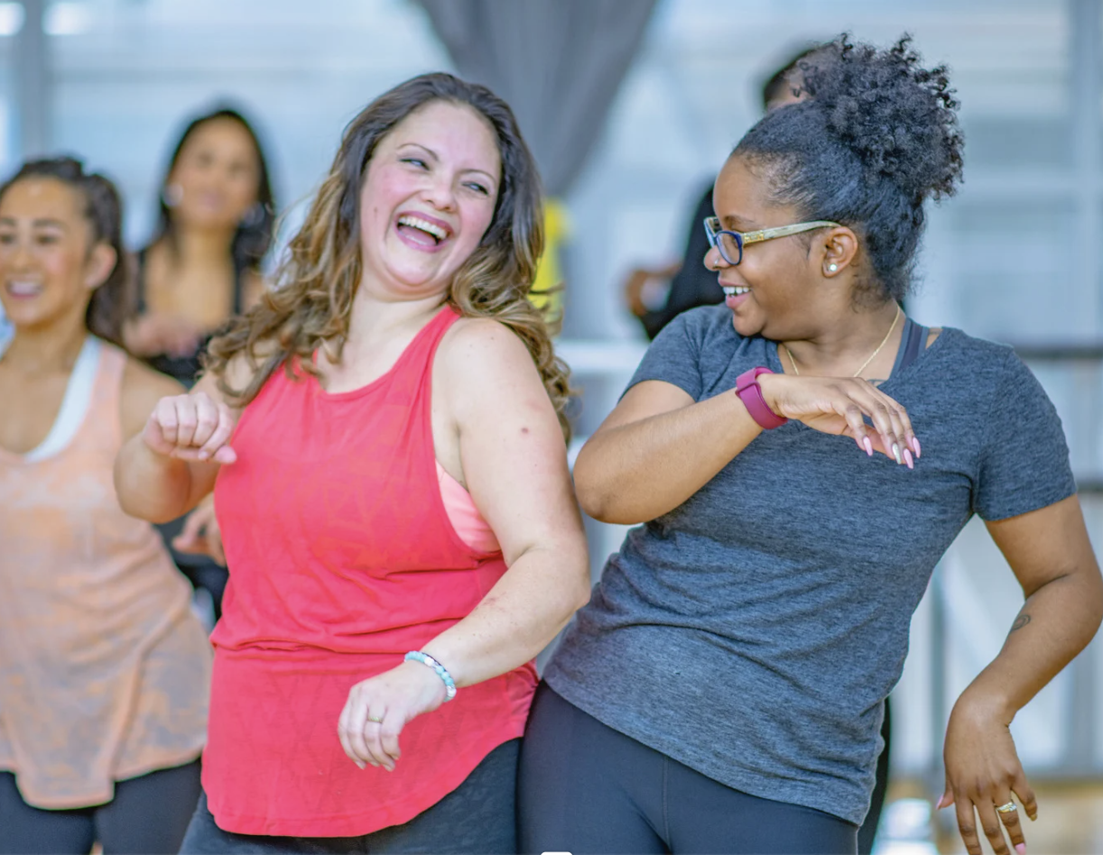 Picture shows women dancing happily, and enjoying each other demonstrating the benefits of dance/movement therapy, including boosting mental health and fostering social connection and building self-esteem.